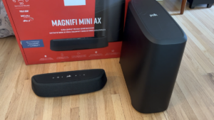Magnify mini sound bar and subwoofer side-by-side on the floor with package in the background